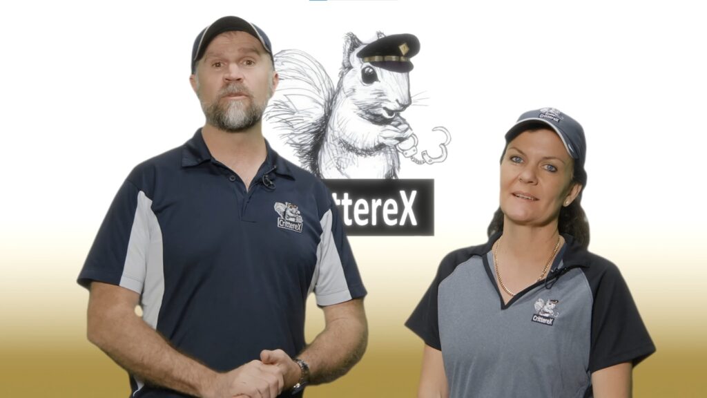A man and a woman wearing navy and grey CrittereX branded polo shirts and caps, standing in front of a background featuring the squirrel mascot logo.